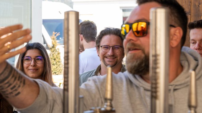 Eine Gruppe von Menschen, die lächeln und interagieren, während einer eine Hand hebt.