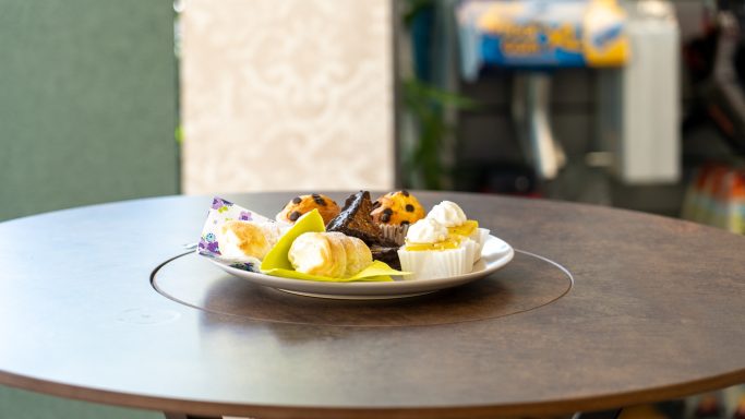 Teller mit verschiedenen Desserts, darunter Kuchen und Früchte, auf einem Tisch.