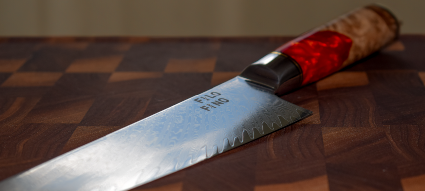 Schneidemesser mit einer holzfarbenen und roten Griffbeschichtung auf einem Holzbrett.