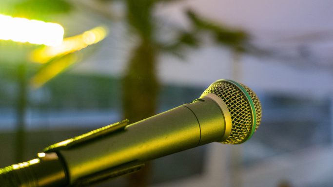 Ein Mikrofon mit grünem Licht in unscharfem Hintergrund.