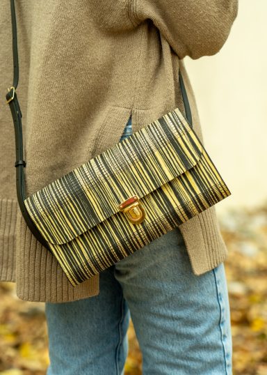 Braune Umhängetasche mit gestreiftem Muster, an einer Person getragen.