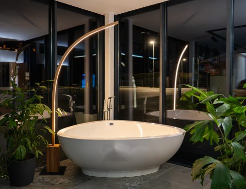 Moderne, freistehende Badewanne in einem eleganten Badezimmer mit Pflanzen und großen Fenstern.